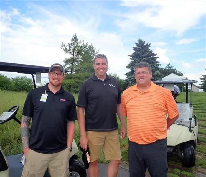 SERVPRO employee standing with two males on golf course