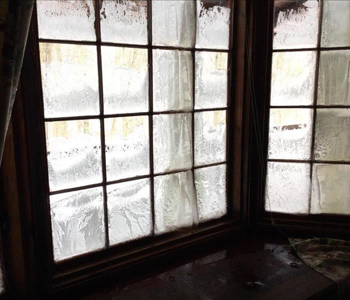 Windows of log cabin with condensation and ice formation