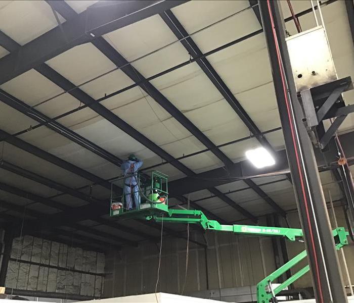 SERVPRO technician on lift cleaning soot from ceiling