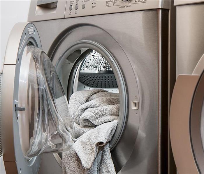 Clothes dryer with towel hanging out of open door